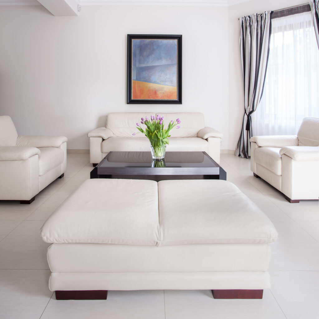 A modern living room with white upholstered sofas and armchairs, showcasing an elegant setting and highlighting the value of upholstery cleaning to maintain cleanliness and freshness, especially when considering upholstery cleaning for white furniture.