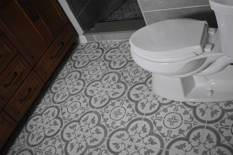 Detail of a bathroom floor after tile and grout cleaning services, highlighting the intricate gray and white tiles and the wooden vanity's craftsmanship